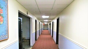 A long hallway with doors on both sides, carpeted floor, and a ceiling with fluorescent lights. - Marifah Inn (Williamsburg)