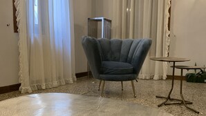 A room with a round table, a blue armchair, and a small table with a lamp. - San Marco Charming Suite apartment (Venezia)