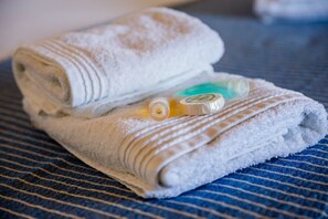 Een bad/douchecombinatie, een haardroger, handdoeken, zeep