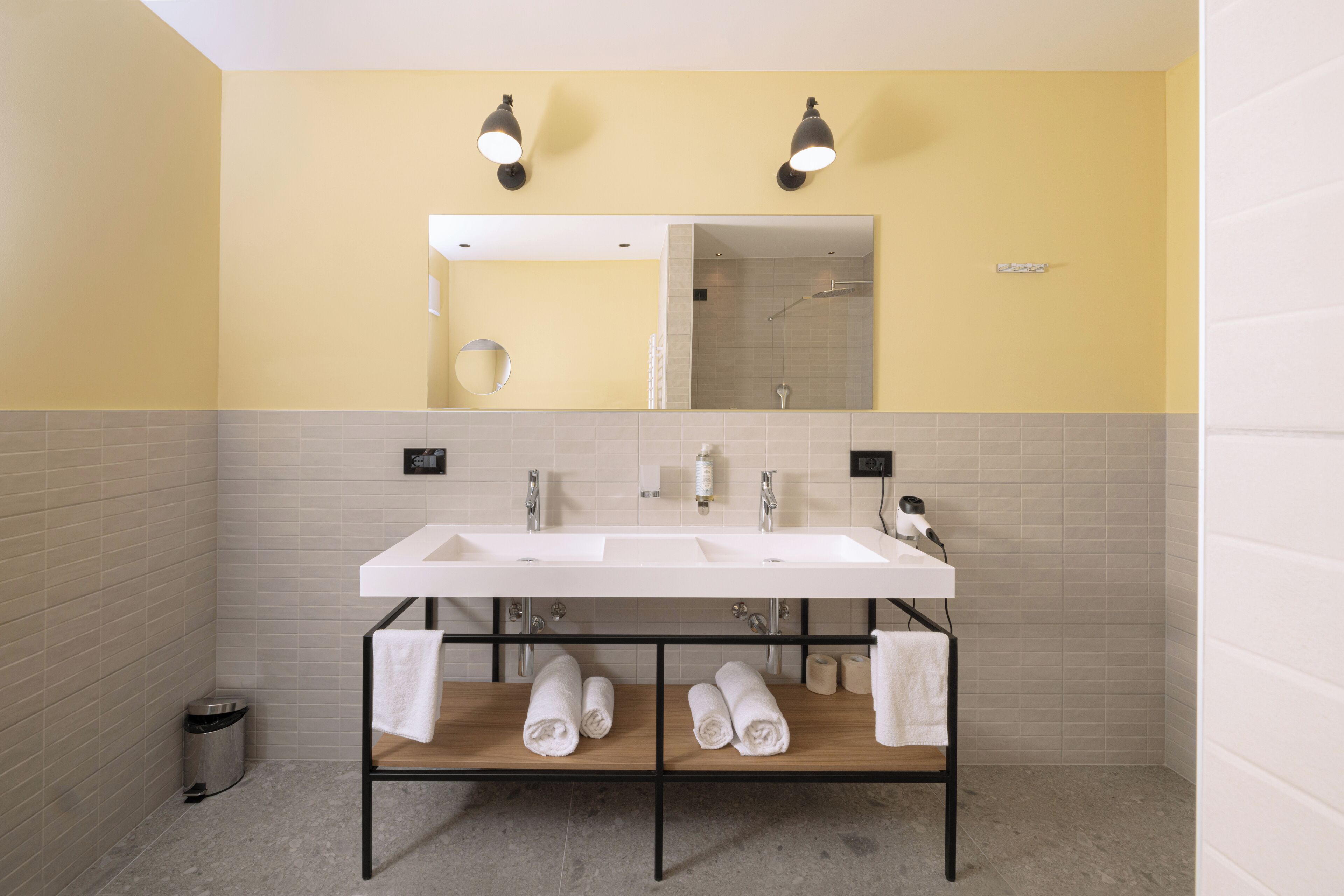 A modern bathroom with two sinks, a mirror, and a towel rack.