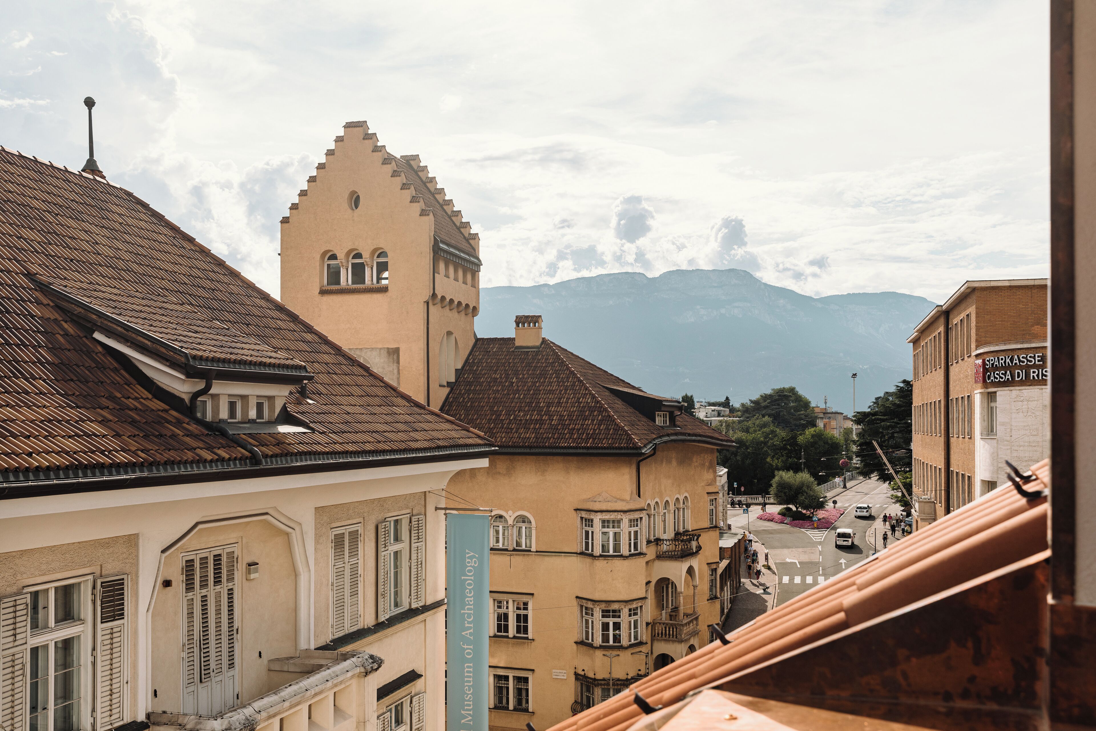 A historic building with a sign for the Museum of Archaeology, a staircase, and a view of mountains in the background.