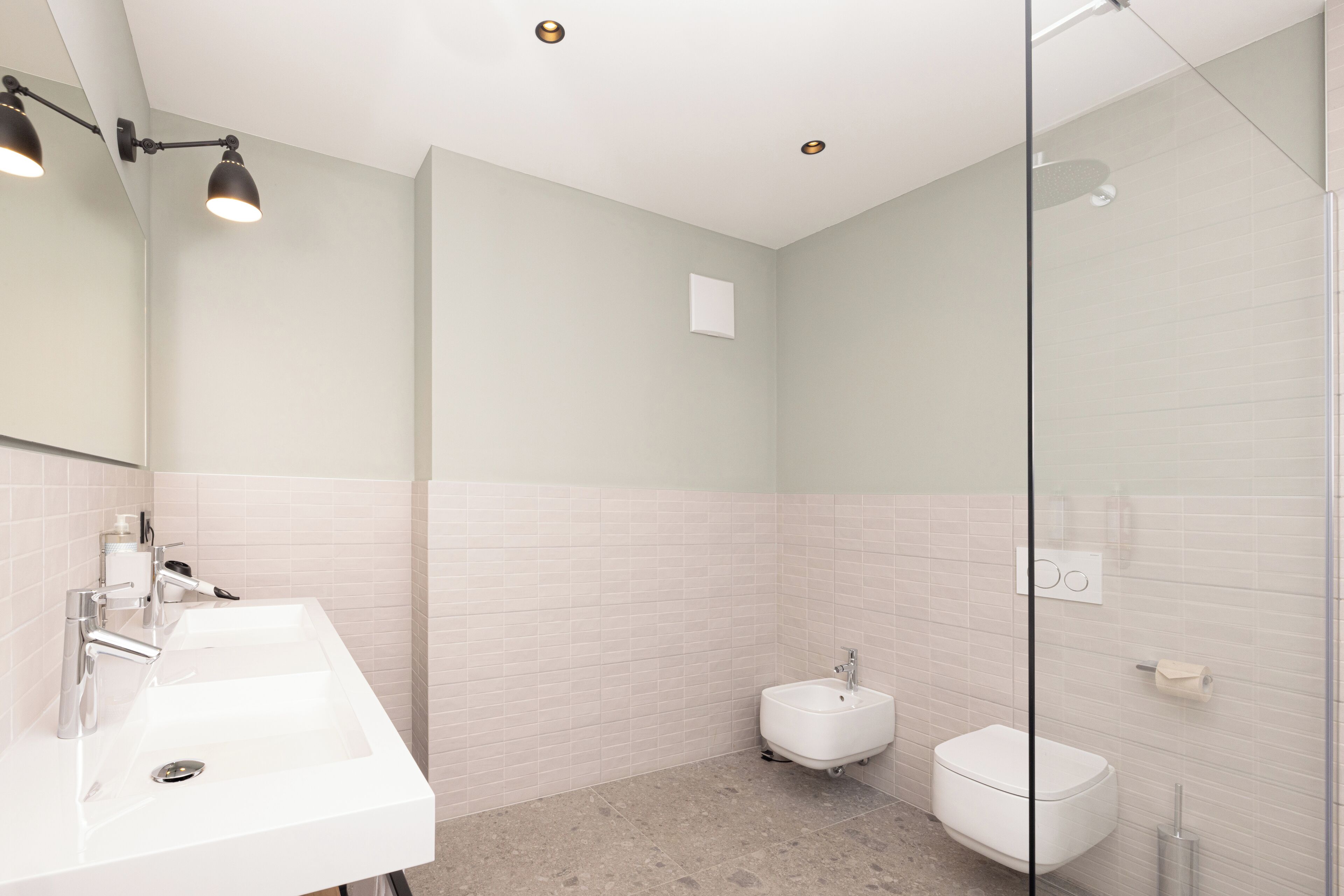 Un baño moderno con un lavabo blanco, un inodoro pequeño y una cabina de ducha de vidrio.