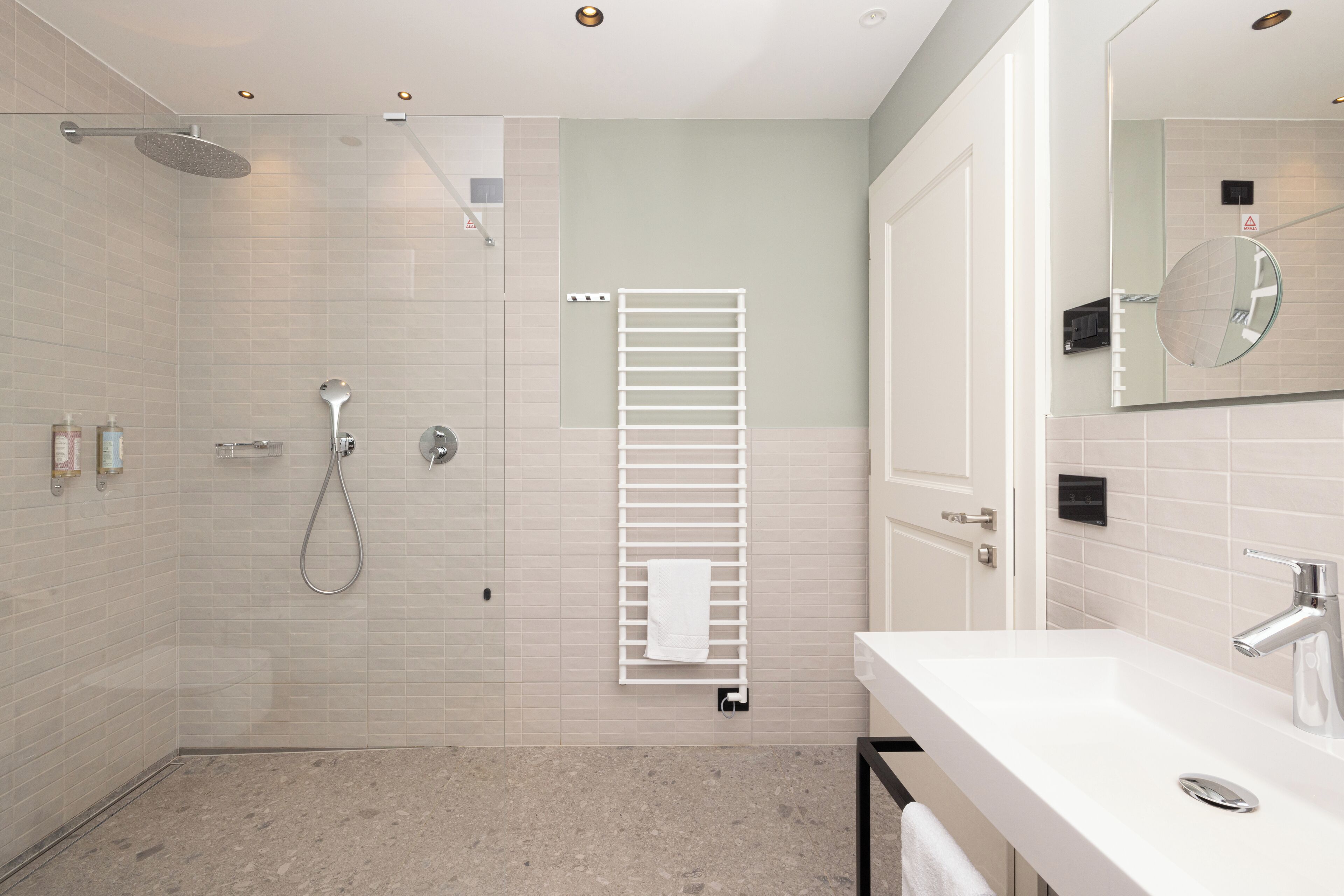 Une salle de bain moderne avec une douche, un lavabo blanc et un miroir.