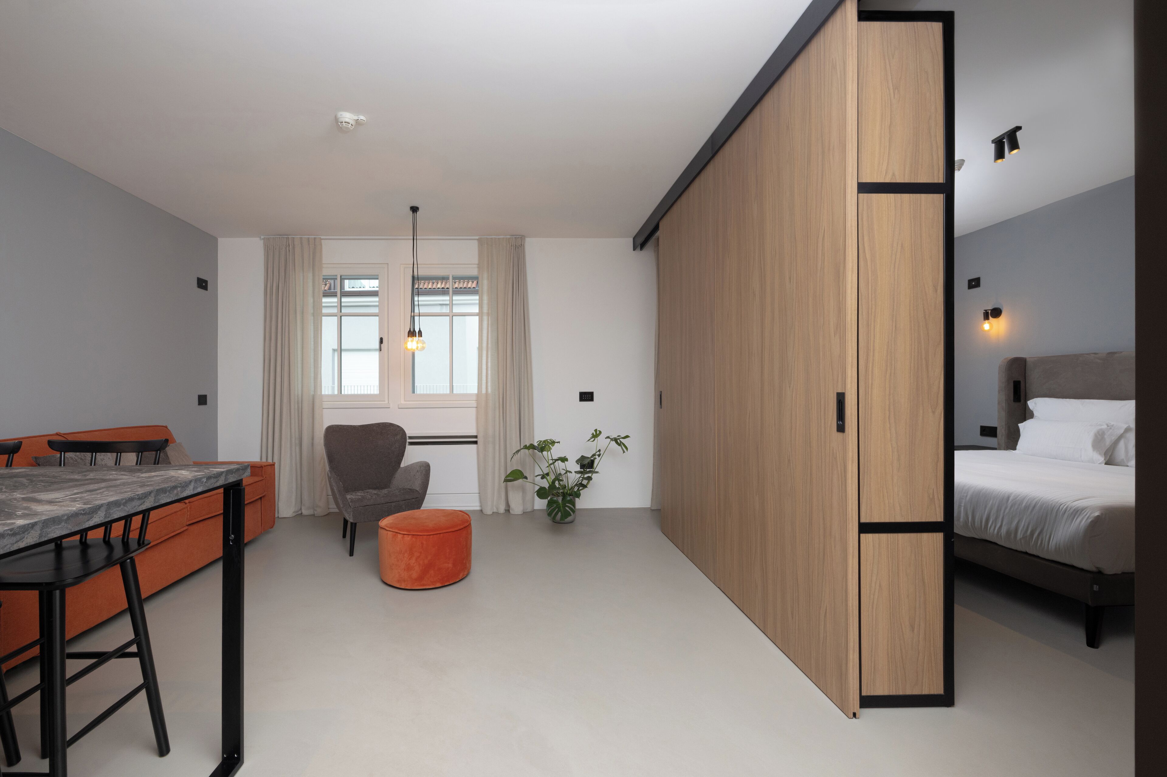 Una habitación moderna con una mesa de comedor, un sofá, una silla, una cama y un amplio armario.