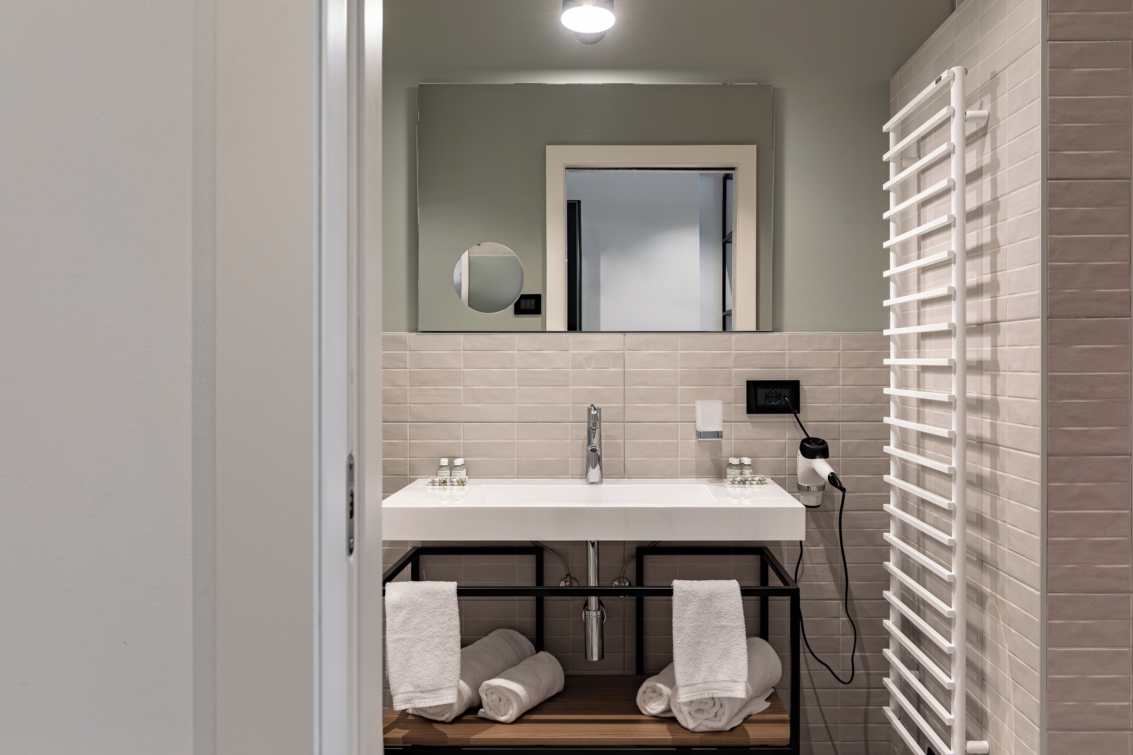 A modern bathroom with a white sink, a mirror, and a towel rack.