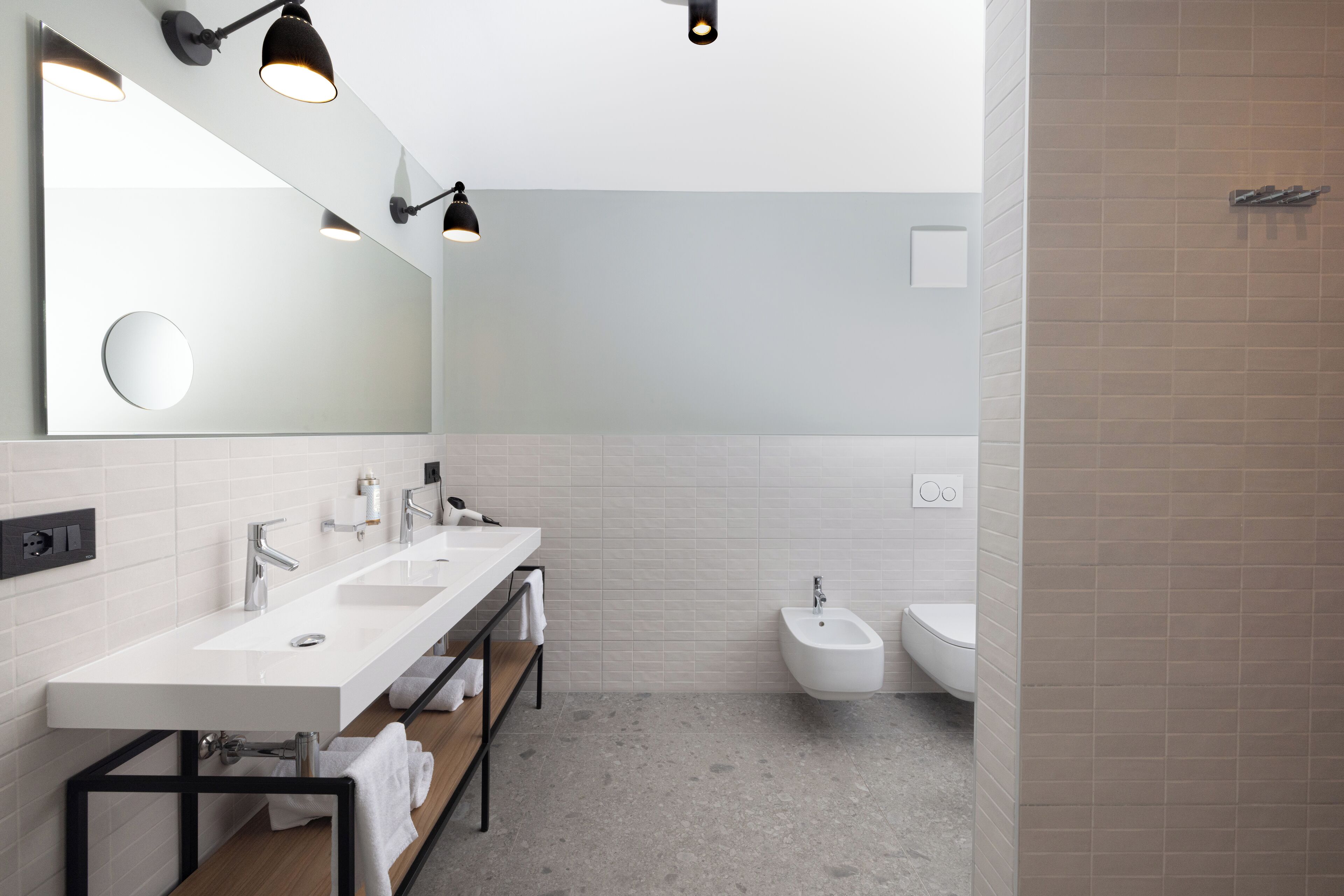 A modern bathroom with two sinks, a bidet, and a large mirror.
