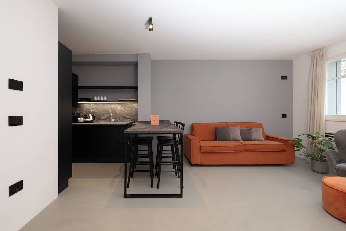 A modern living room with a dining area, a kitchen, and a sofa.