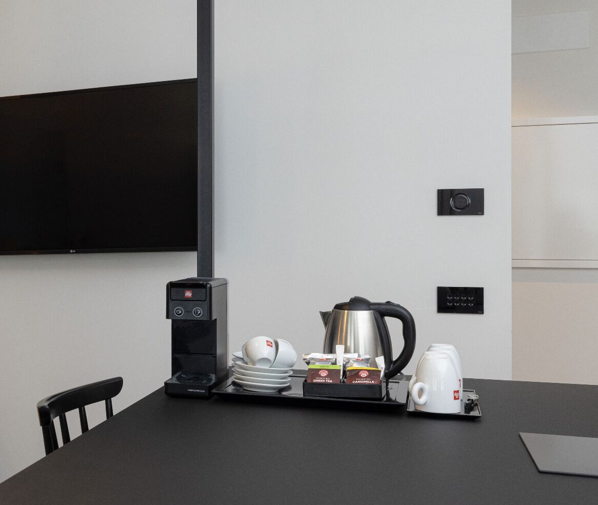 Une salle de conférence équipée d’une table noire, d’une machine à café, d’une bouilloire, ainsi que de sachets de thé et de café.