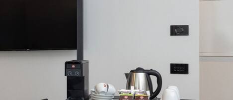A conference room with a black table, a coffee machine, a kettle, and tea and coffee packets.