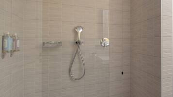 A modern shower with a handheld showerhead and a wall-mounted control.