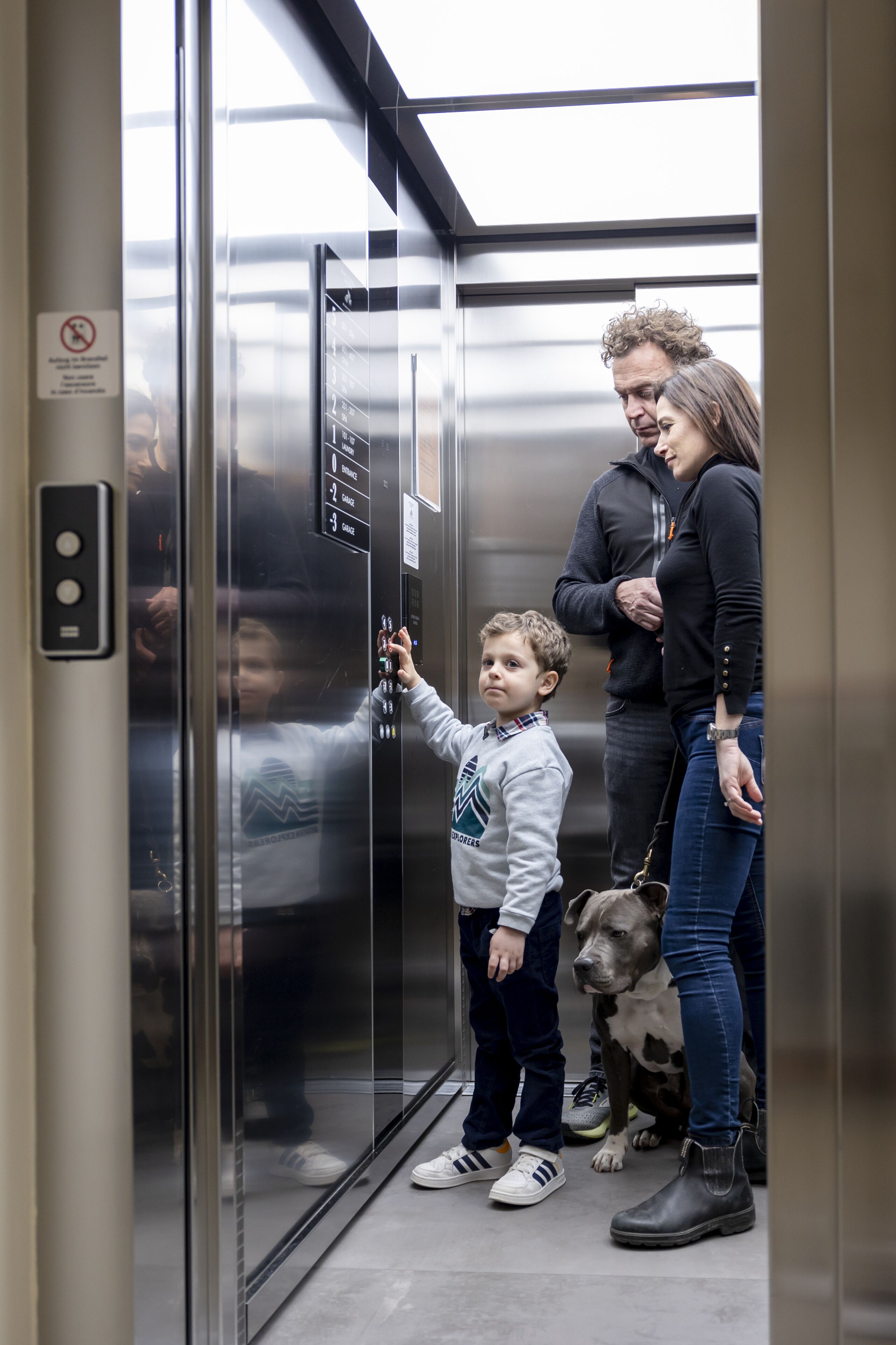 A family inside an elevator with a dog.