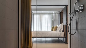 A modern hotel room with a glass partition, a bed, a shower, and a view of the outside. - Residence - Palais Hörtenberg (Bolzano)