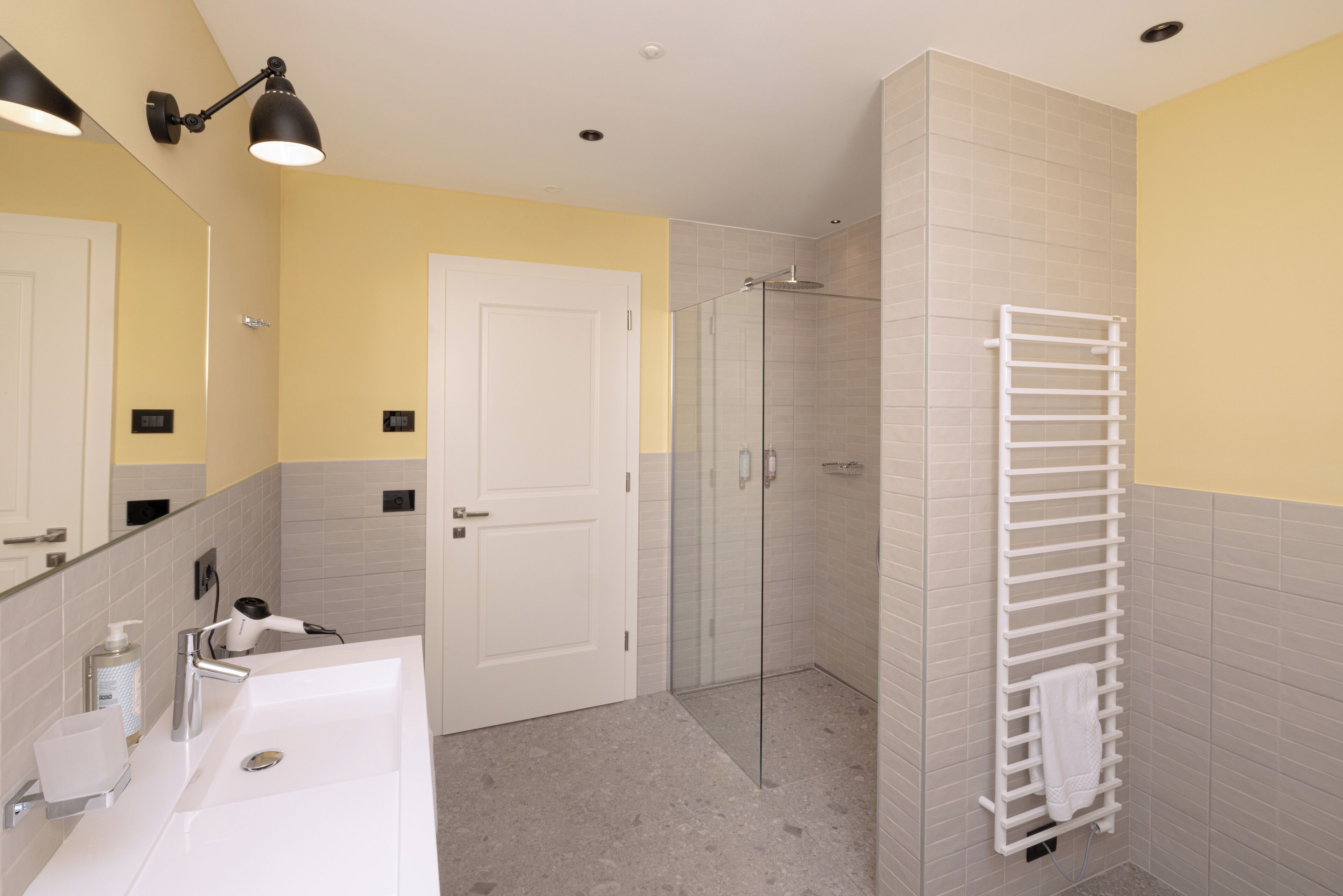 Een moderne badkamer met een wit wastafelmeubel, een glazen douchecabine en een handdoekhouder.