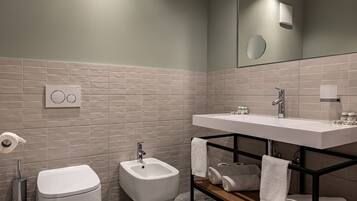 A modern bathroom with a bidet, toilet, and a large mirror above the sink.