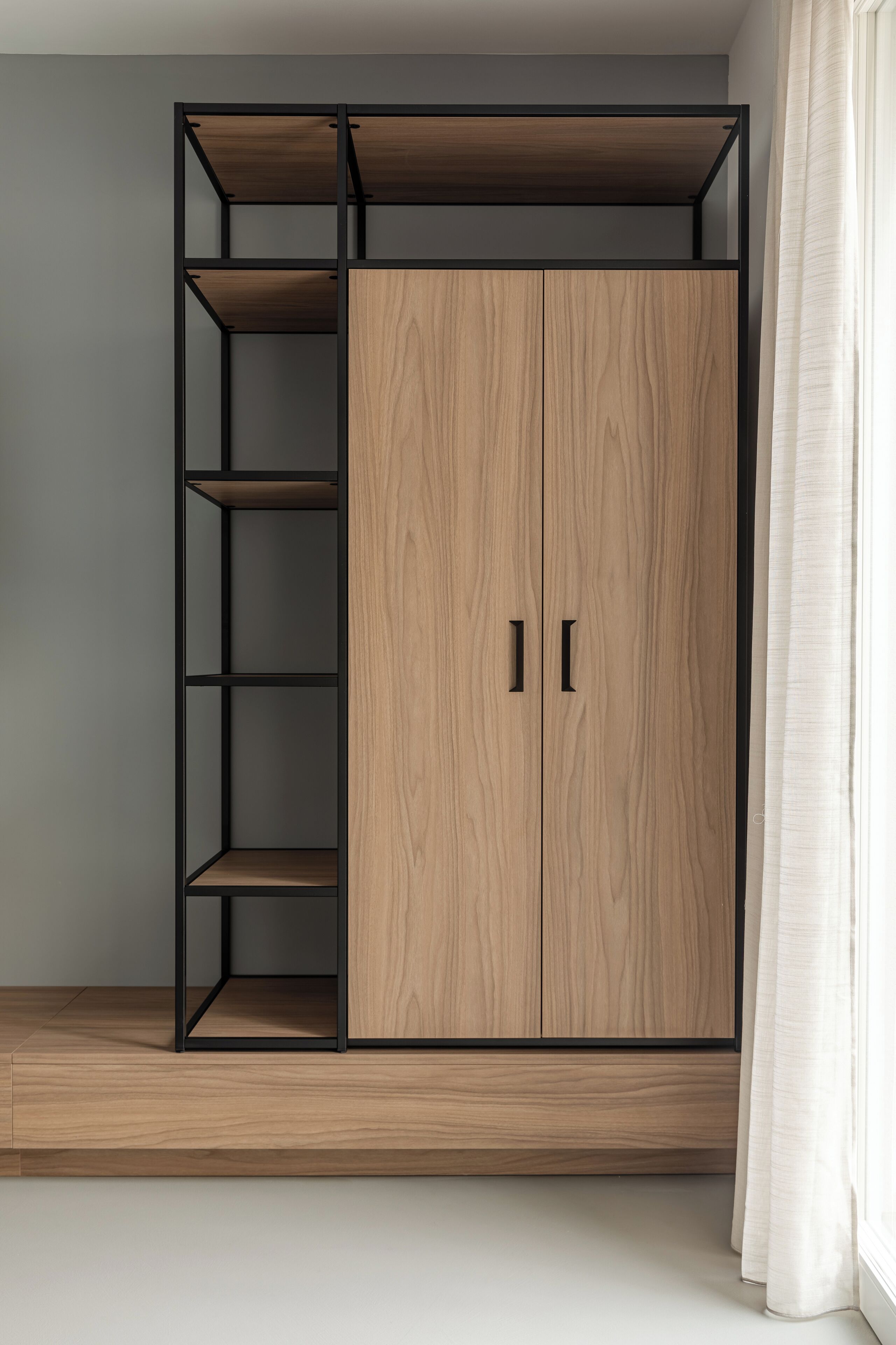 Een moderne kast met meerdere planken en een houten afwerking, voor een effen muur.