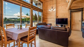 Ein rustikaler Blockhausaustattung mit Essbereich, einer Couch und einem Fernseher.