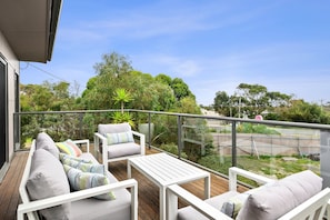 Ein Balkon mit einer Couch, Stühlen und einem Tisch.