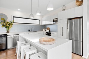 A modern kitchen with a large island, stainless steel appliances, and white cabinetry.