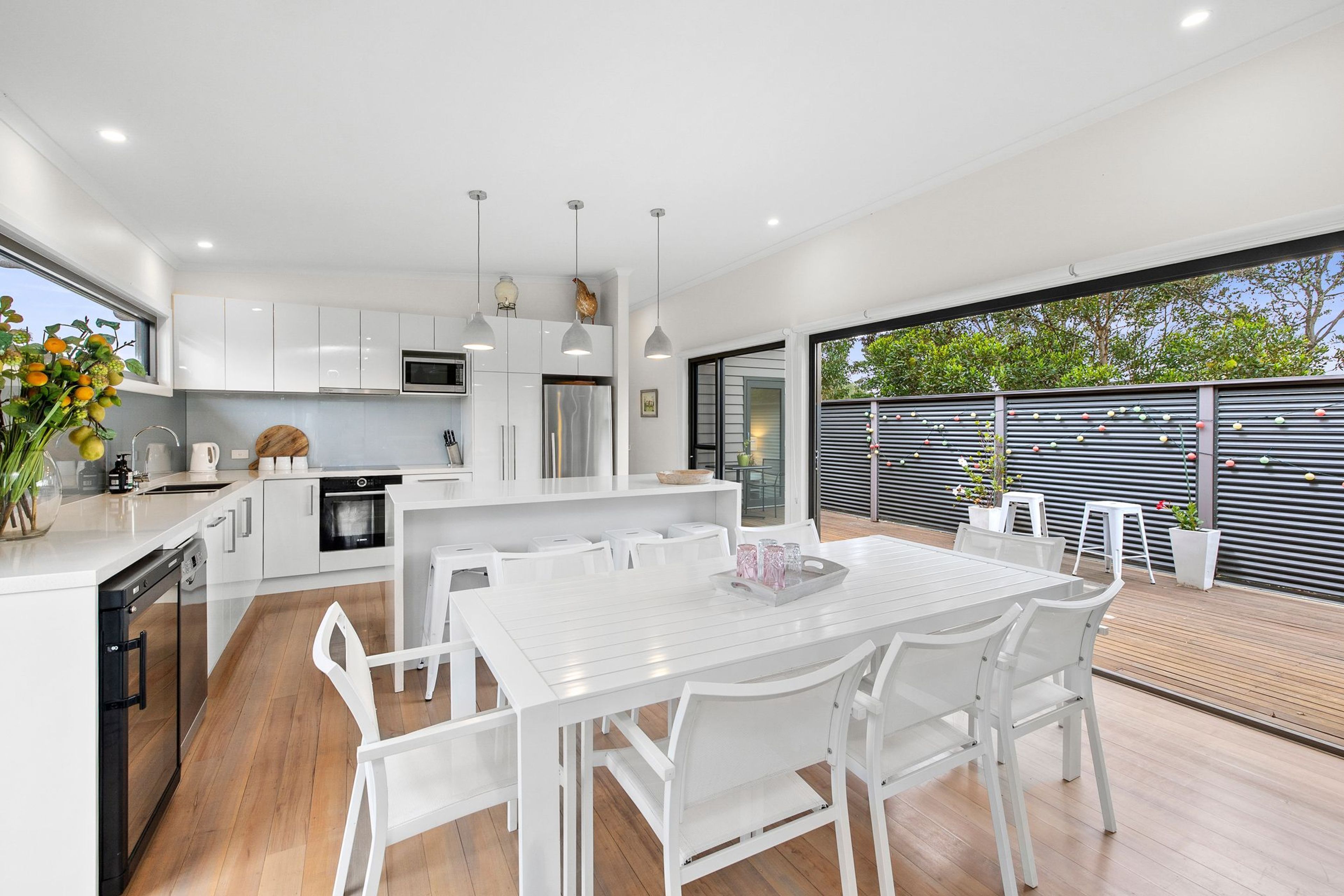 A modern kitchen with white cabinetry, stainless steel appliances, and pendant lighting.