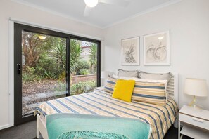 A bedroom with a bed, a nightstand, a lamp, and two framed artworks on the wall.