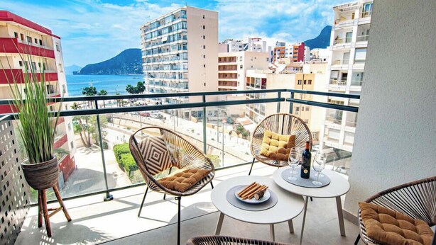 A balcony with wicker chairs, a small table, and a potted plant. - A016 - ARENAL SUITES - AVANOA (Calpe)