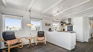 A modern kitchen with white cabinetry, a central island, and a dining area with two chairs. - Pet friendly home in Vejers Strand (Vejers Strand)