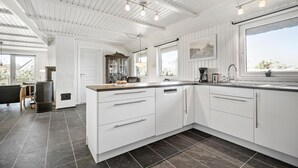 A modern kitchen with white cabinetry, a central island, and a large window providing natural light. - Pet friendly home in Vejers Strand (Vejers Strand)