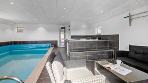 A modern indoor pool area with a reception desk, seating, and a clear view of the pool. - Pet friendly home in Vejers Strand (Vejers Strand)
