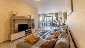 Una sala de estar moderna con un televisor de pantalla plana, chimenea, sofá y un comedor con sillas y mesa.