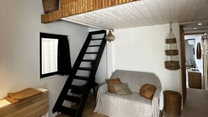 Ein Loft-Wohnraum mit Holzbalkendecke, einer Treppe, einer Couch, einem Fernseher und einem Blumentopf.