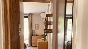 Ein Korridor mit einer Holztür, einem kleinen Holzschrank und einem hängenden Korb.