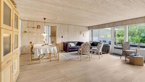 Une pièce spacieuse comprenant un coin repas, un canapé et une grande fenêtre donnant sur l’extérieur.