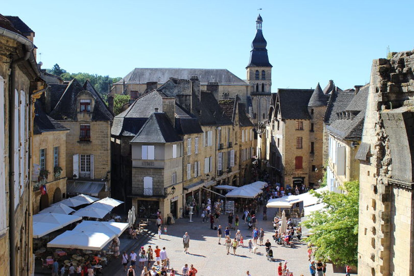 A historic town square with traditional buildings, a prominent church tower, and outdoor market stalls.