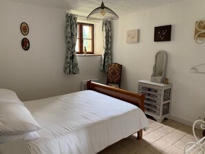 Une chambre à coucher comprenant un lit, une commode, une chaise, une fenêtre avec des rideaux et des éléments de décoration murale.
