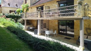 Un bâtiment en pierre doté d’un balcon, d’un espace extérieur aménagé pour s’asseoir et d’un jardin.