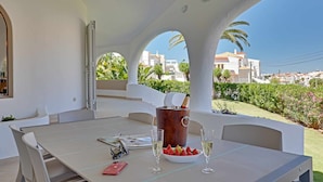 A dining area with a table, chairs, a wine bucket, glasses, and a bowl of strawberries. - Villux - Villa Enar - 6 rooms, ideal for families. (Albufeira)