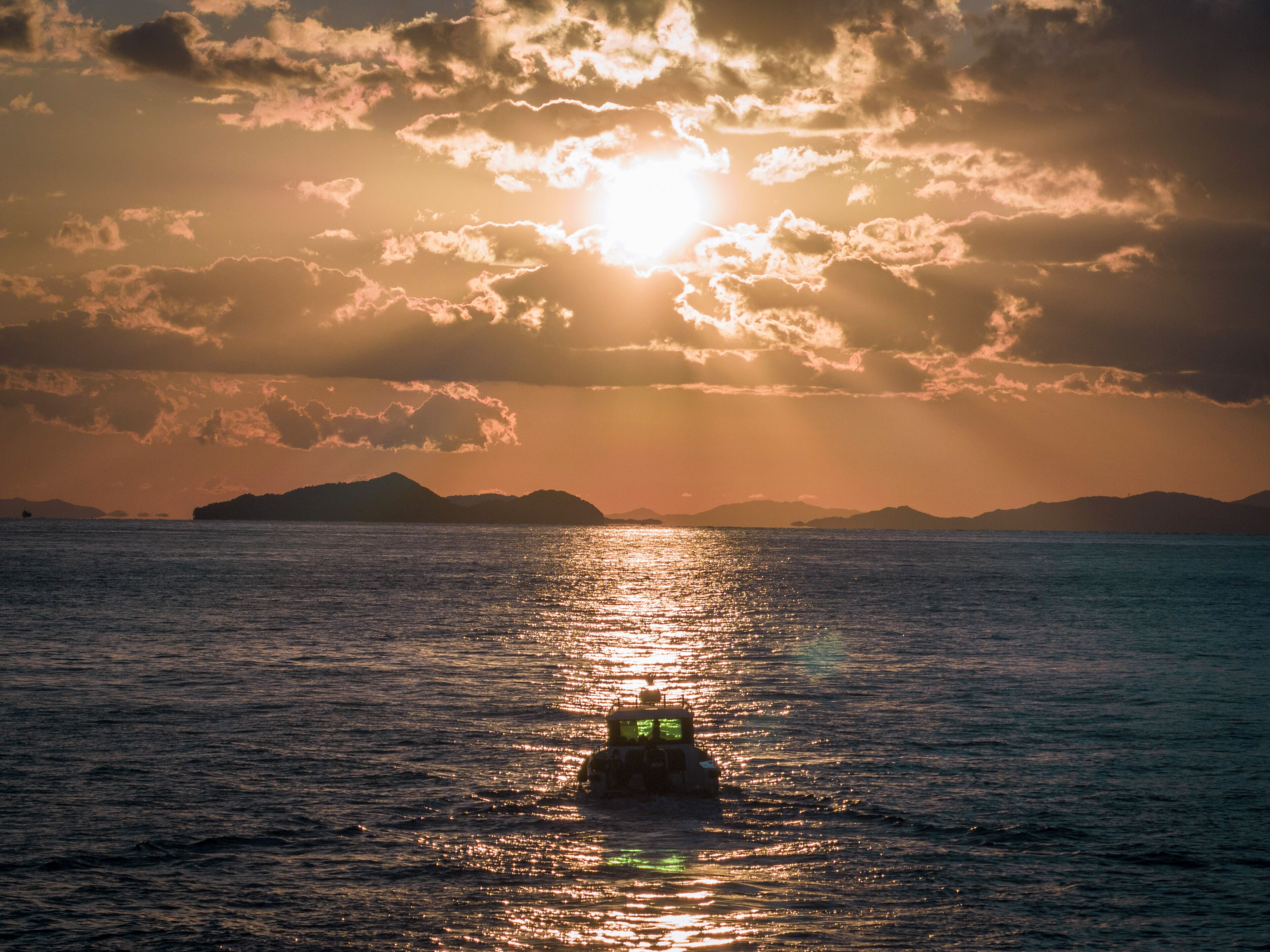 A boat on calm waters with a sunset in the background.