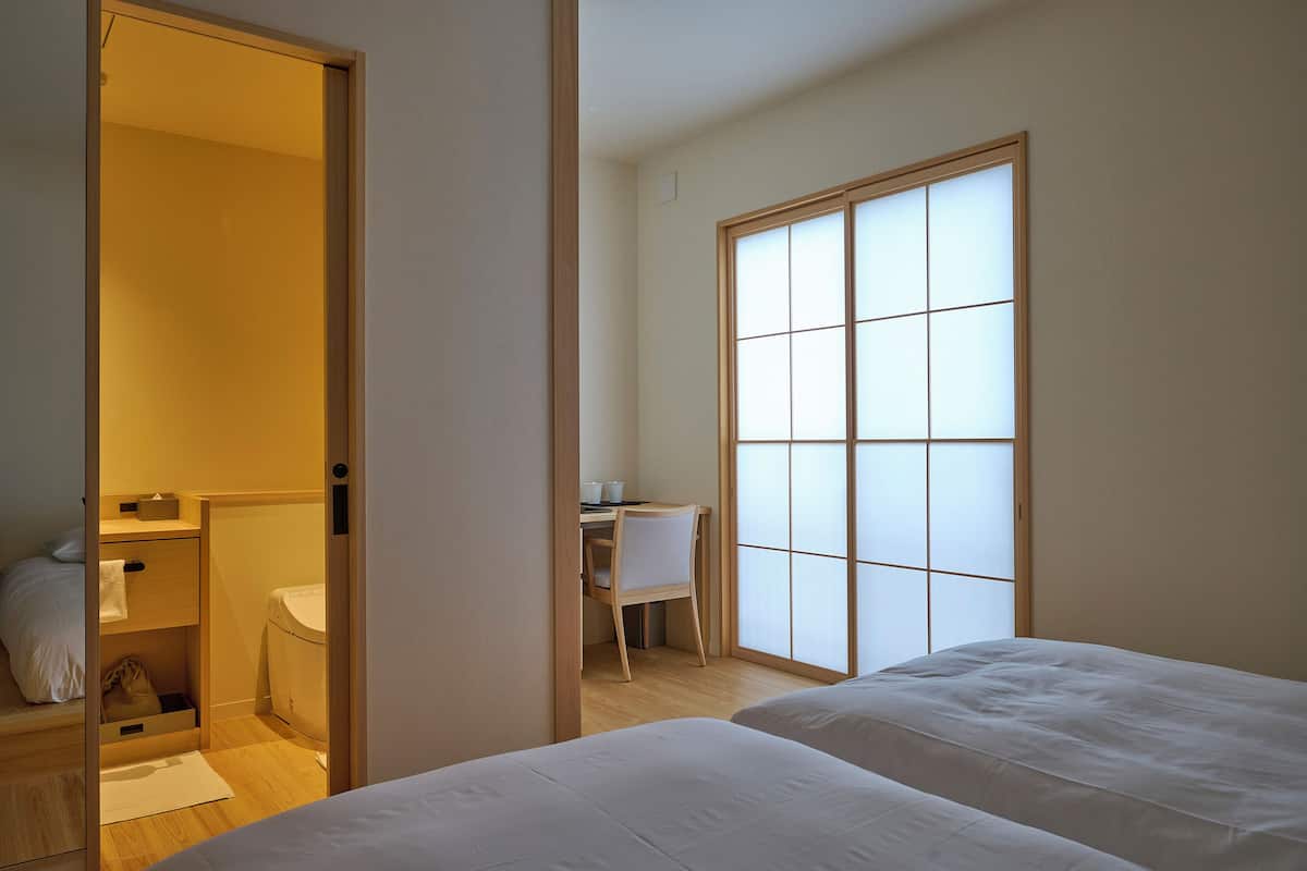 Une chambre avec deux lits, un bureau, une chaise et des toilettes.