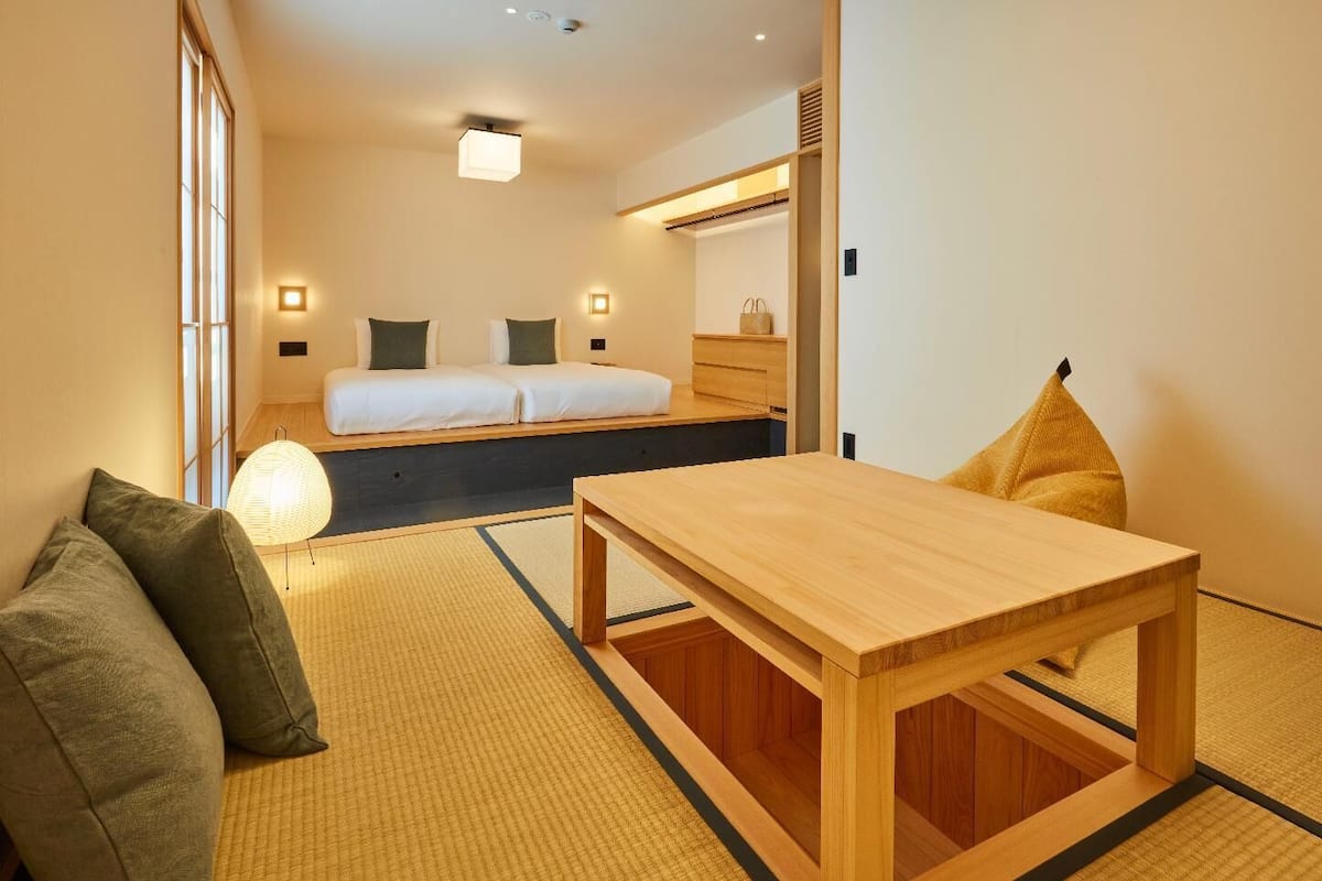 Une pièce de style japonais traditionnel, avec un sol recouvert de tatamis, une petite table en bois et un futon servant de lit.