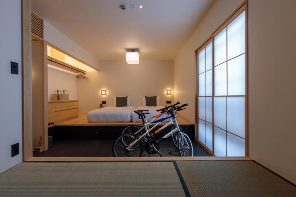 A hotel room with a bed, two bedside tables, a bicycle, and a sliding shoji screen door.