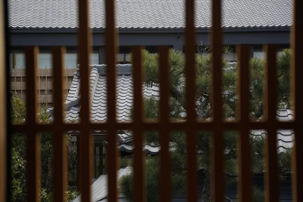Ein traditionelles japanisches Gebäude mit einem Ziegeldach und Blick durch eine Holzzakenzaun.