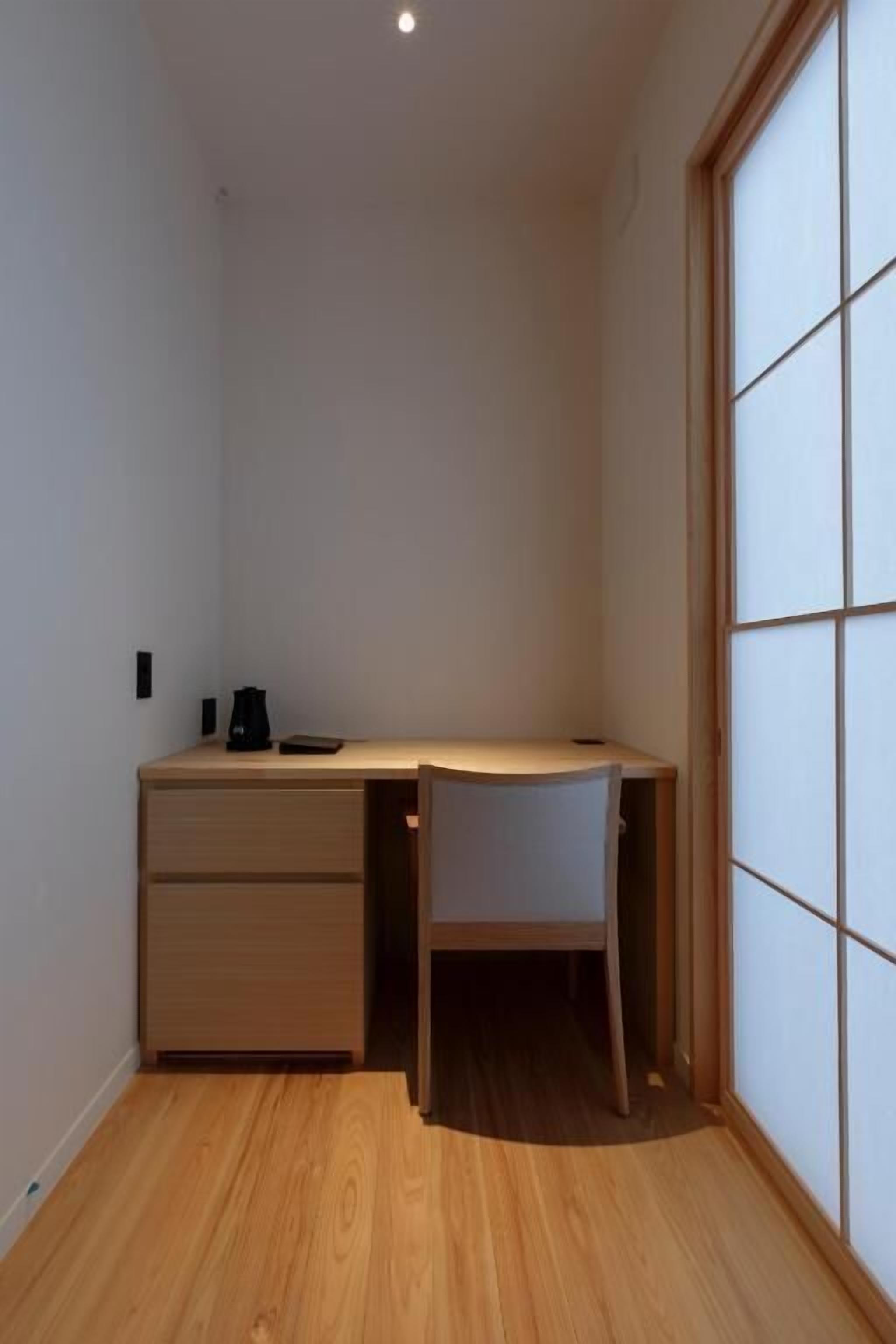A small, modern room with a wooden desk, a chair, and a sliding shoji screen door.