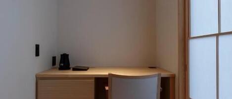 A small, modern room with a wooden desk, a chair, and a sliding shoji screen door.