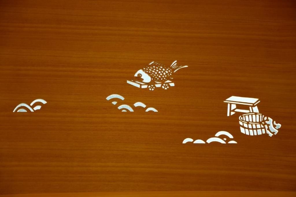 A wooden surface with a white fish, a table, and a barrel.