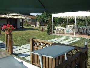 Un espace extérieur aménagé en terrasse, avec une plateforme en bois, une table et des chaises, ainsi qu’un coin salon abrité.