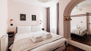 A bedroom with a bed, bedside tables, a mirror, and a window with curtains.