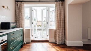 A kitchen with a microwave, green cabinets, and a view through an open door to a balcony.
