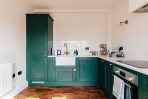 A kitchen with teal cabinets, a white sink, and a stainless steel oven.