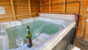 A hot tub with a bottle of wine and two glasses, wooden walls, and a sign warning not to stand on the hot tub cover. - Burns Cottage (Barnard Castle)