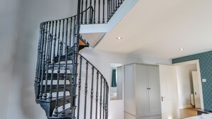 A bedroom with a wooden floor, a white wardrobe, and a spiral staircase with black railings. - Burns Cottage (Barnard Castle)